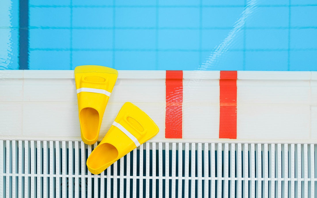 Yellow swim fins on the edge of a swimming pool