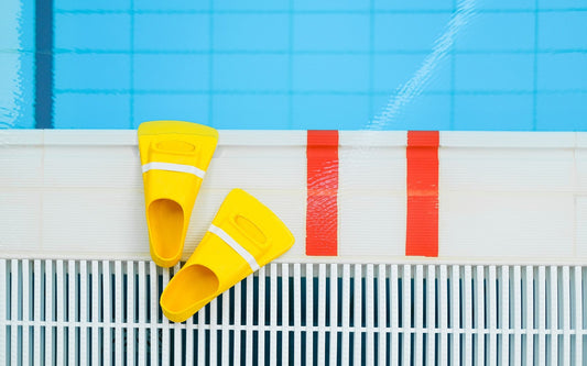 Yellow swim fins on the edge of a swimming pool
